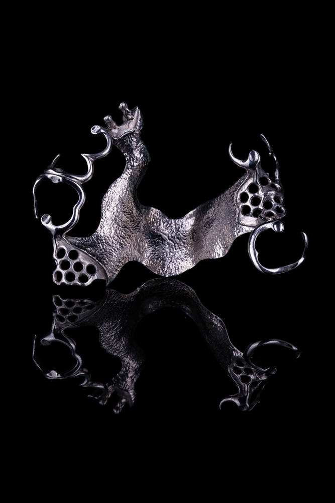 Cast cobalt-chrome partial denture framework on a black background