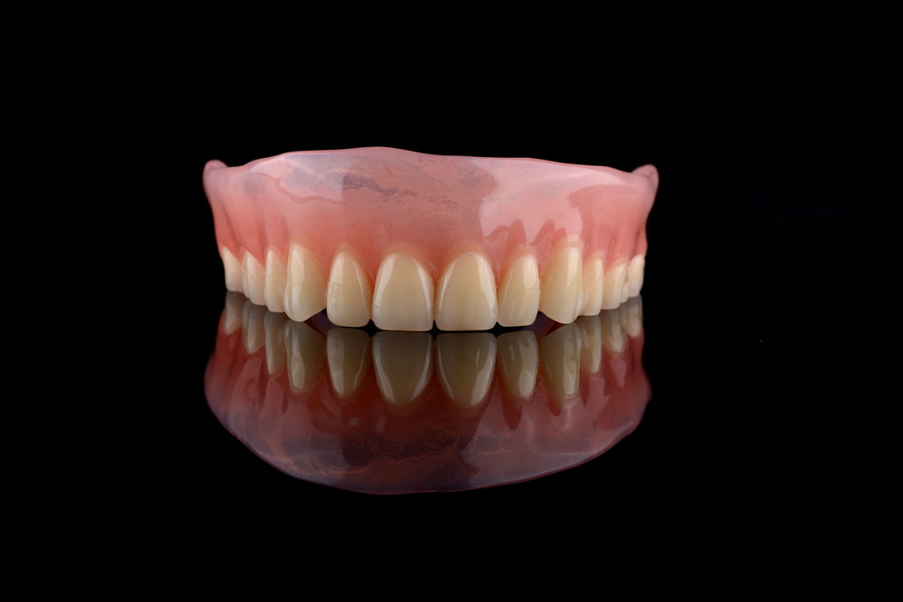 Complete upper denture on a black reflective surface